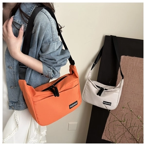 Close-up of nylon crossbody dumpling bag showing wide strap and cord zipper details