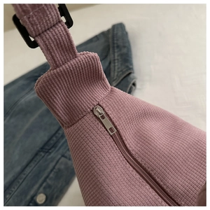 Detail of pink corduroy bag showing black plastic buckle and silver metal zipper
