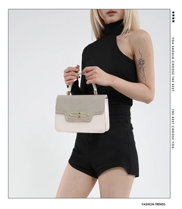 Close-up of stylish contrast color crossbody bag with woven texture and gold clasp