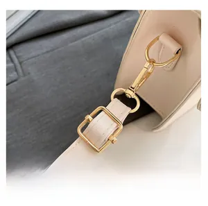 Close-up of adjustable cream leather shoulder strap with polished gold metal hardware