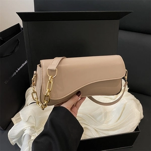 Minimalist beige crossbody bag with unique asymmetric curved flap and gold chain strap