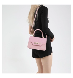 Detail view of pink crossbody bag with metal lock and textured leather stitching