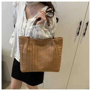 Detail of woven straw tote bag with silver chain and brown leather strap texture
