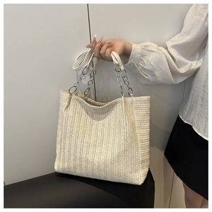 Detail of off-white woven tote bag featuring silver chain straps and herringbone texture