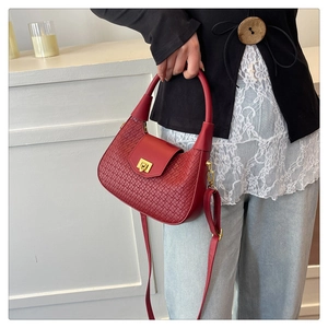 Detail of red woven leather handbag featuring a gold metal lock and adjustable strap