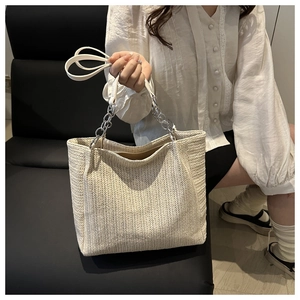 Detail of woven beige tote bag featuring silver chain straps and fine leather shoulder strap
