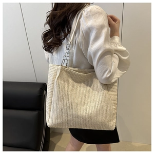 Detailed macro view of woven cream straw texture and chic silver chain shoulder strap