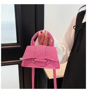 Detail of bright pink woven texture handbag featuring a trendy hourglass shape and strap