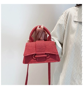 Close-up of red woven hourglass handbag with textured handle and buckle detail