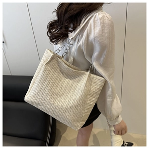 Detailed close-up showing the textured herringbone weave and metal chain strap of the tote bag