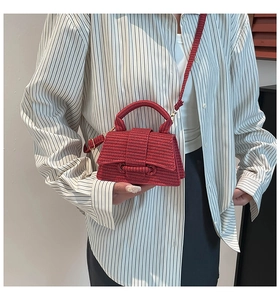 Detailed view of red woven texture hourglass mini bag worn as a crossbody by model