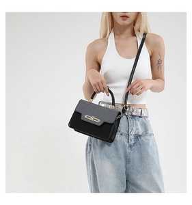 Detail of color-block crossbody bag with elegant golden metal lock on light studio background