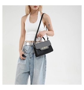 Detail of a two-tone crossbody bag with smooth black leather and pebble-textured flap
