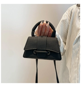 Detail of black hourglass handbag featuring unique wave texture and curved top handle