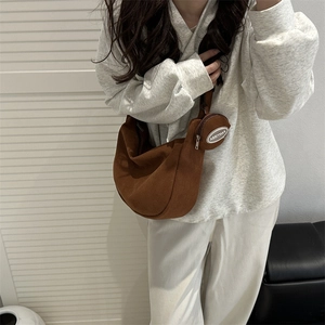 Brown corduroy crescent shoulder bag with small coin pouch worn by model in casual style