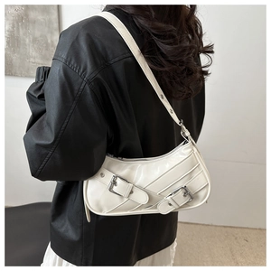 Détail du sac sous le bras en cuir crème avec des boucles décoratives en métal argenté
