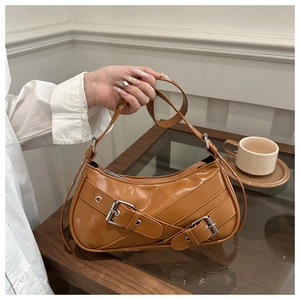 Détail du sac bandoulière en cuir verni caramel avec boucles argentées décoratives