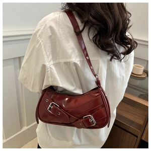 Detail of burgundy patent leather baguette bag with silver buckles on white shirt