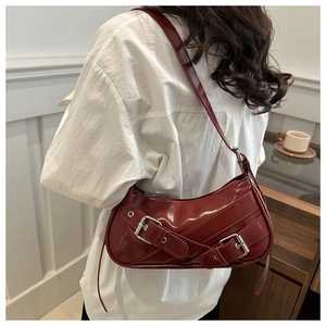 Détail du sac sous le bras rouge foncé style motard avec boucles argentées et fini brillant