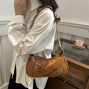 Sac sous le bras caramel brillant avec boucles porté par un mannequin en chemise