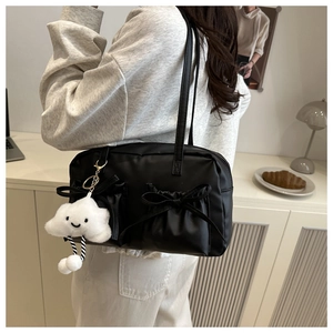 Détail du sac bandoulière noir avec poches à nœuds et charm nuage souriant sur un modèle