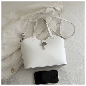 Detailed top view of white bucket bag size comparison with a smartphone on textured fabric