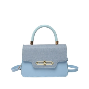 Minimalist light blue crossbody bag with textured fabric flap and gold metal hardware
