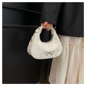 Detailed view of cream hobo bag featuring textured fabric and silver bow embellishment