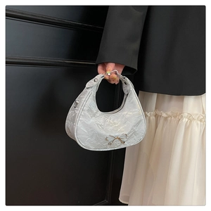 Detailed shot of silver bow handbag featuring pleated metallic texture and half-moon shape