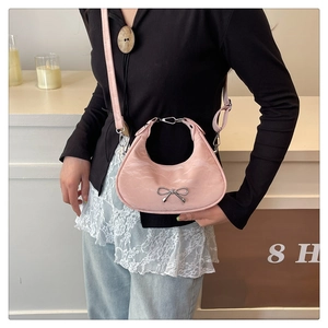 Close-up of pink crescent moon bag featuring a silver metal bow and textured faux leather