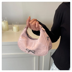 Close-up of pink crescent hobo bag with a silver metallic bow and textured nylon finish