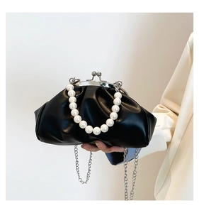 Detail of black pleated cloud bag featuring large pearl handle and silver chain strap