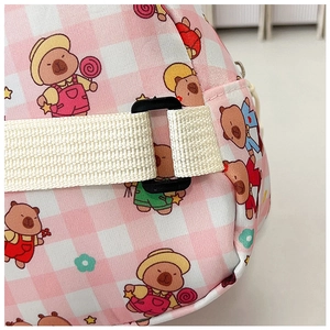 Detail of cartoon bear print on pink checkered fabric with adjustable strap and buckle