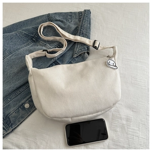 Detail of cream corduroy crescent bag featuring striped texture and cute puppy pendant