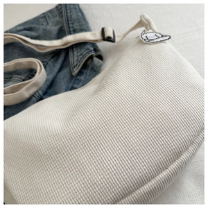 Detail of white corduroy tote bag featuring adjustable strap and cute puppy patch