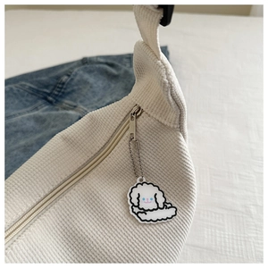Detail of white corduroy tote bag with metal zipper and cute cartoon animal pendant