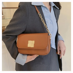 Close-up of brown leather shoulder bag featuring gold square buckle and chain strap