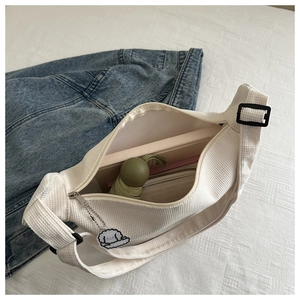 Detail of white corduroy crescent bag showing large capacity for umbrella and notebook