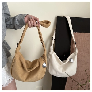 Detailed corduroy fabric texture on khaki and cream crescent bags with cute dog charms