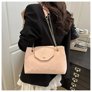 Detail of pink snakeskin pattern shoulder bag with gold chain strap on a model