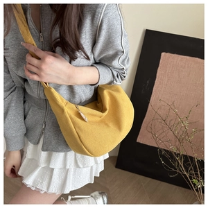 Detail of yellow corduroy crescent bag with wide shoulder strap and silver zipper puller