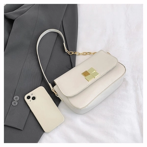 Detailed close-up of cream leather bag with a unique gold and silver square metal clasp