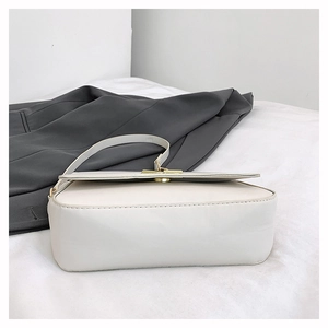Detailed bottom view of cream leather baguette bag with golden metal twist lock closure