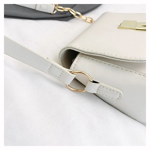 Detail of white leather shoulder bag featuring gold hardware and precise stitching