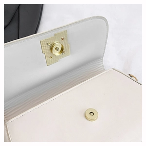 Detailed close-up of golden magnetic closure on cream white faux leather flap bag
