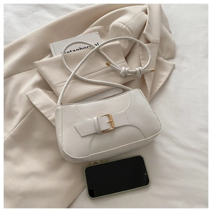 Detail of beige leather baguette bag with gold buckle and a smartphone for size reference