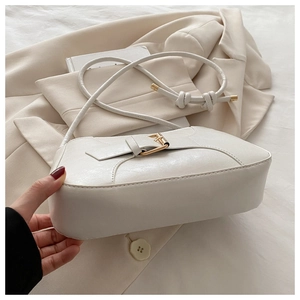 Detail of creamy white baguette bag with golden buckle and sleek leather texture