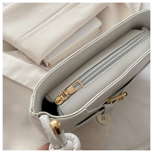 Detail view of smooth zipper and gold hardware on white leather shoulder bag