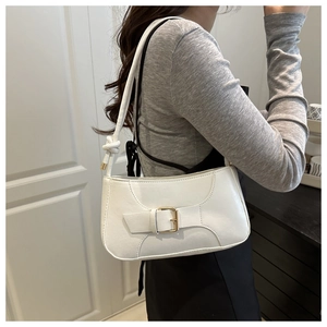 Detailed side view of white faux leather baguette bag with strap buckle and knot accents