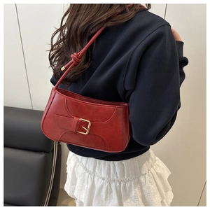 Detail of red vintage baguette bag with gold buckle and knotted shoulder strap on model